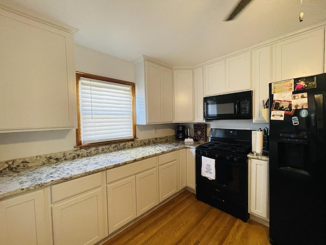 kitchen with white cabinets, dark hardwood / wood-style flooring, light stone countertops, and black appliances