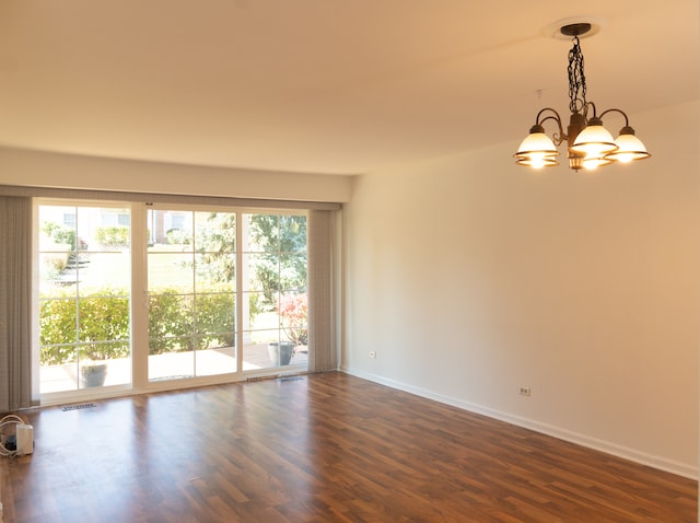 unfurnished room featuring an inviting chandelier and dark wood-type flooring