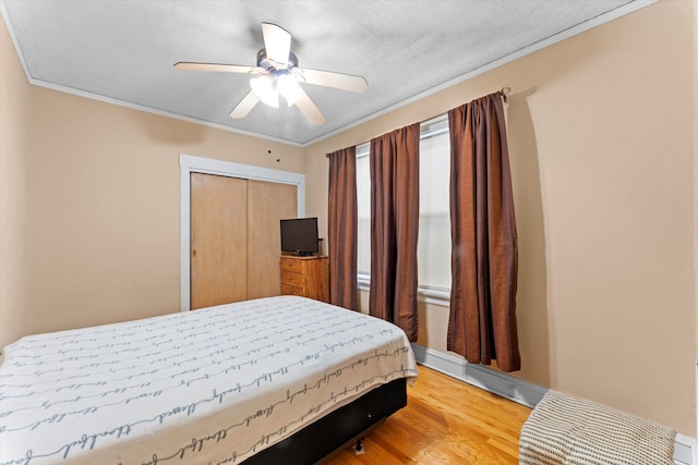 bedroom featuring a closet, wood-type flooring, crown molding, and ceiling fan