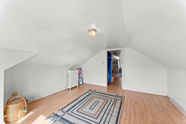 additional living space featuring lofted ceiling, hardwood / wood-style floors, and radiator