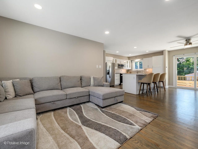 living room featuring dark wood-type flooring and ceiling fan