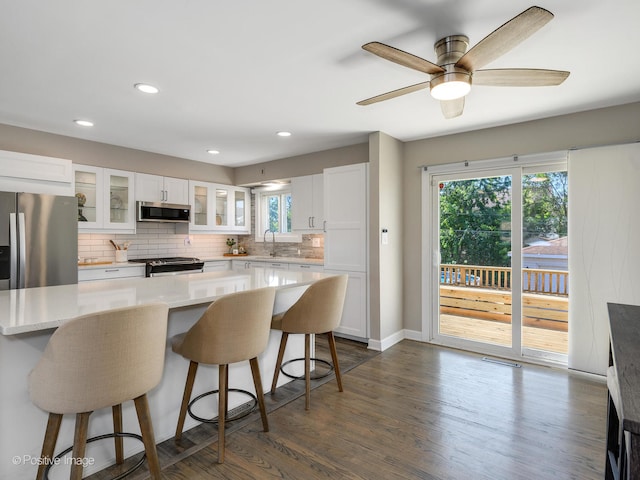 kitchen with dark hardwood / wood-style floors, stainless steel appliances, sink, a center island, and white cabinetry