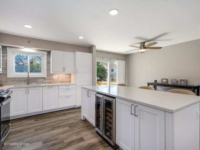 kitchen with stainless steel electric stove, wine cooler, backsplash, dark hardwood / wood-style flooring, and white cabinetry