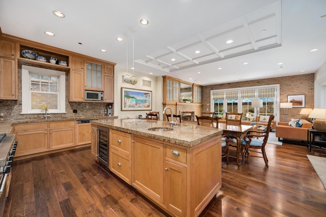 kitchen with coffered ceiling, stainless steel appliances, a center island with sink, sink, and dark hardwood / wood-style flooring