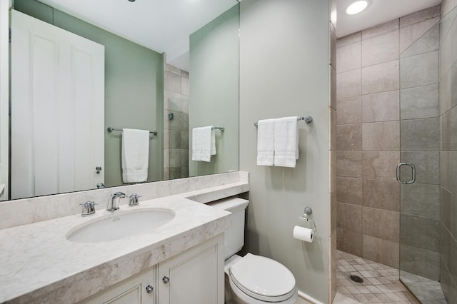 bathroom with toilet, a shower with shower door, and vanity