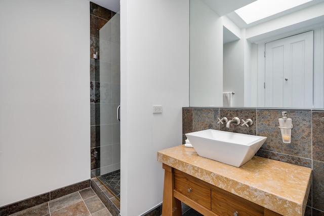 bathroom featuring a shower with door, decorative backsplash, vanity, and a skylight