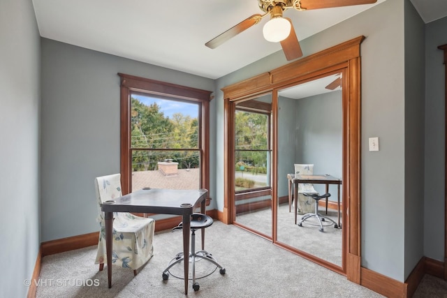 carpeted office space featuring a ceiling fan and baseboards