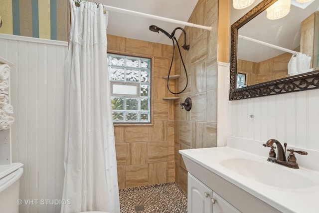 full bath with toilet, a tile shower, and vanity