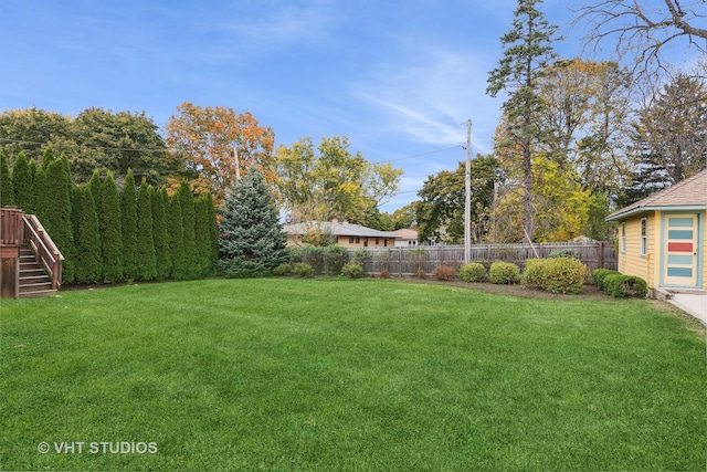 view of yard with a fenced backyard and stairs