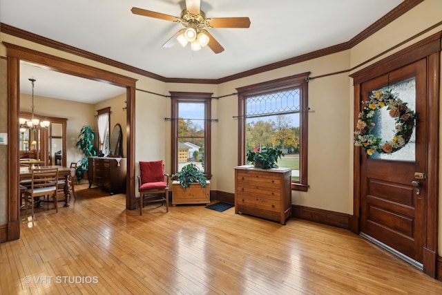 entrance foyer featuring light hardwood / wood-style floors, ornamental molding, and ceiling fan with notable chandelier