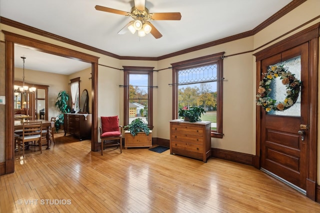 sitting room featuring ornamental molding, light wood finished floors, and ceiling fan with notable chandelier