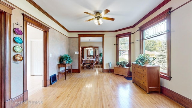 interior space with light wood-type flooring, a ceiling fan, ornamental molding, and baseboards
