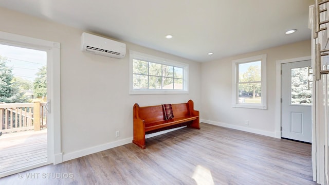 sitting room with baseboards, recessed lighting, wood finished floors, and an AC wall unit