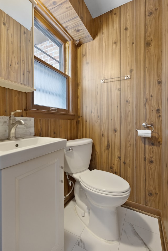 bathroom featuring wood walls, vanity, and toilet