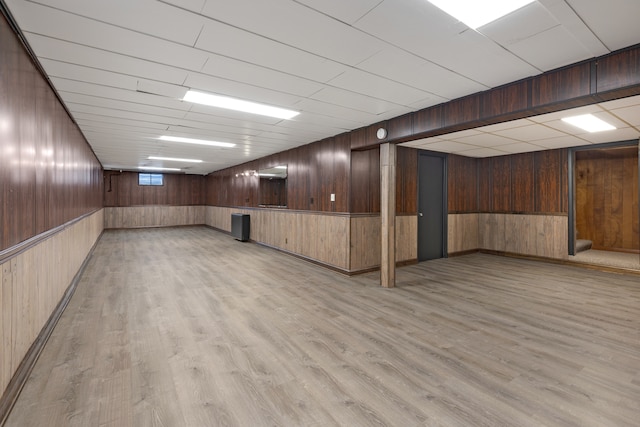 basement with light wood-type flooring and wooden walls