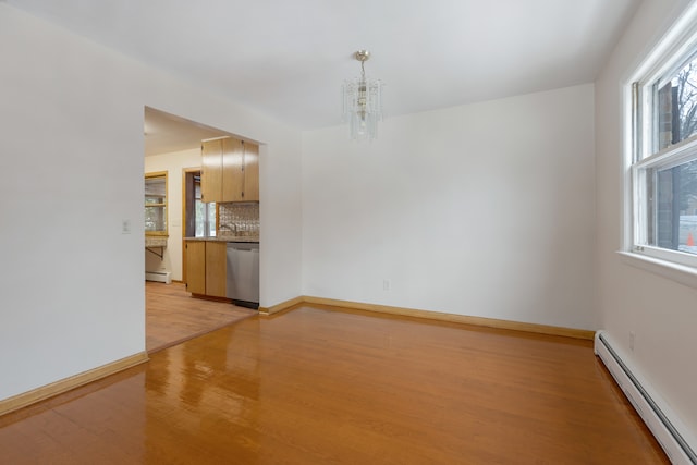 unfurnished room with sink, light wood-type flooring, a baseboard heating unit, and a notable chandelier