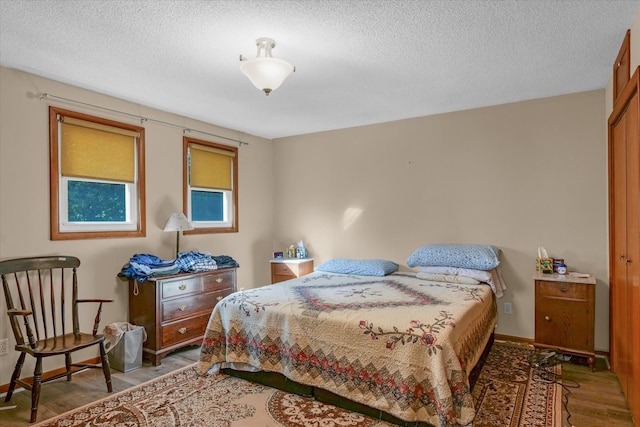 bedroom featuring dark wood-type flooring, a textured ceiling, and a closet