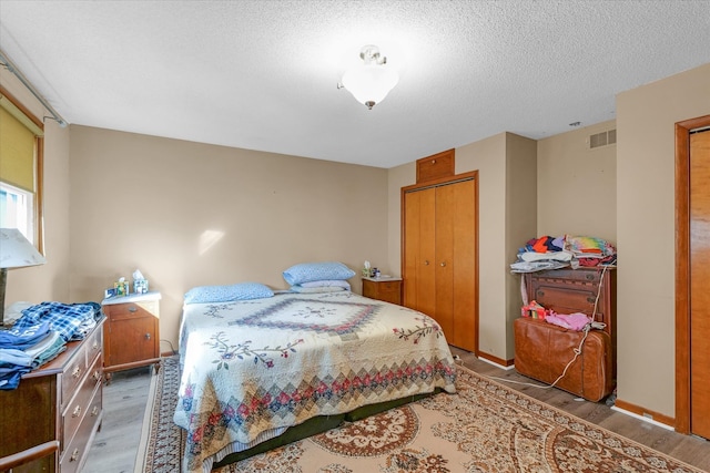 bedroom featuring a textured ceiling, wood-type flooring, and a closet