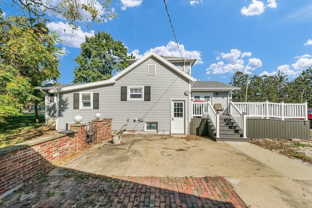 back of house featuring a wooden deck and a patio