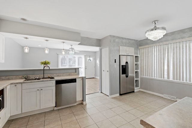 kitchen with appliances with stainless steel finishes, sink, ceiling fan with notable chandelier, decorative light fixtures, and white cabinets