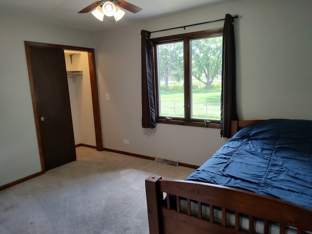 bedroom featuring a closet, ceiling fan, a walk in closet, and light colored carpet