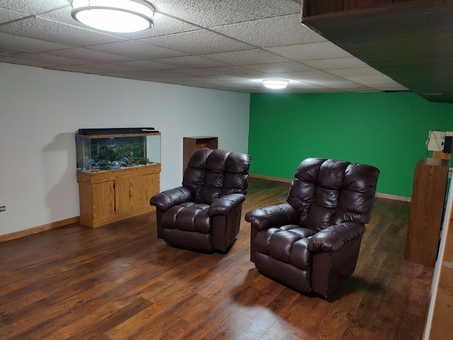 living room with dark wood-type flooring and a drop ceiling