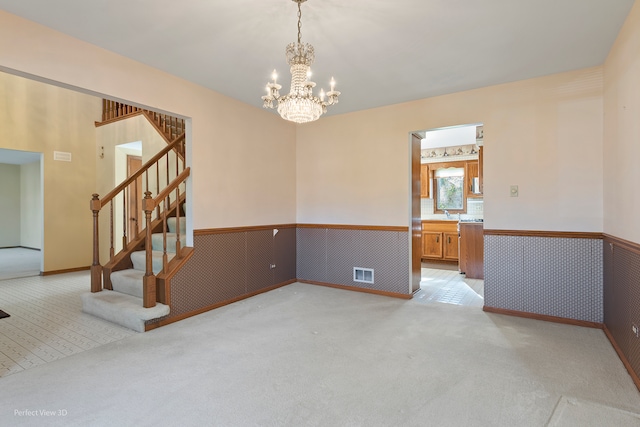 carpeted empty room with an inviting chandelier