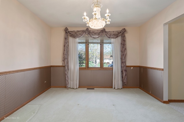 empty room featuring a chandelier and carpet