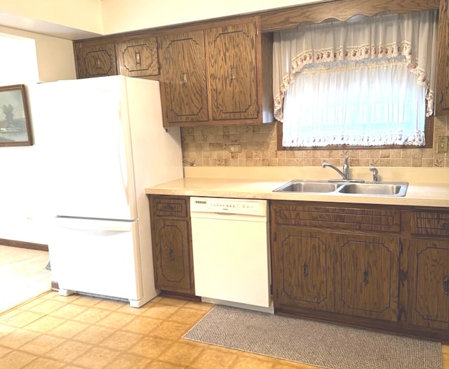 kitchen featuring white appliances, backsplash, and sink