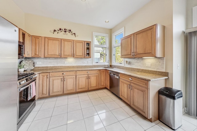 kitchen featuring tasteful backsplash, appliances with stainless steel finishes, sink, light tile patterned flooring, and light stone counters