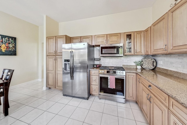 kitchen featuring light stone countertops, tasteful backsplash, appliances with stainless steel finishes, and light tile patterned flooring