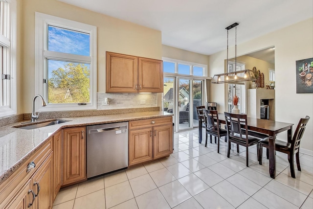 kitchen with tasteful backsplash, light stone countertops, sink, dishwasher, and pendant lighting