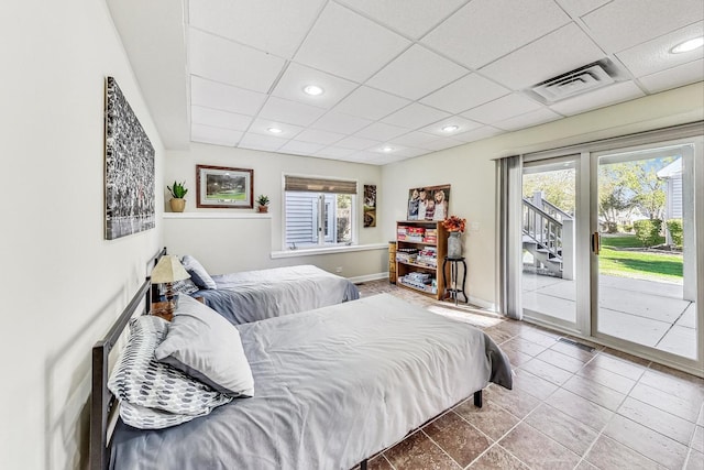 bedroom with a drop ceiling, multiple windows, and access to outside