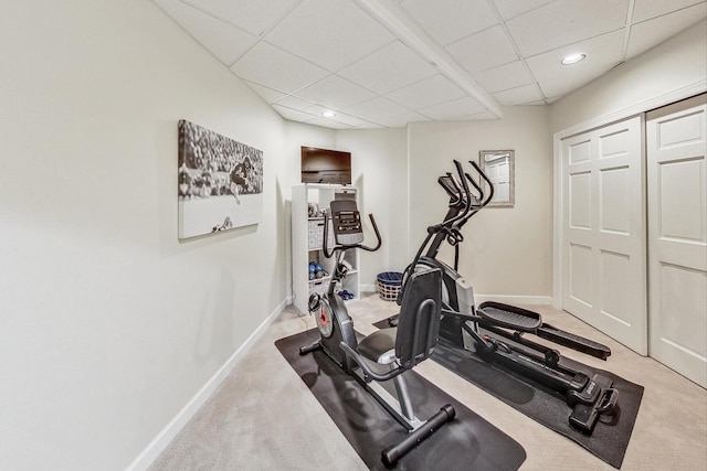 exercise room featuring a drop ceiling and light colored carpet