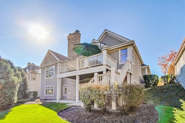 rear view of house featuring a wooden deck, a patio, and a lawn