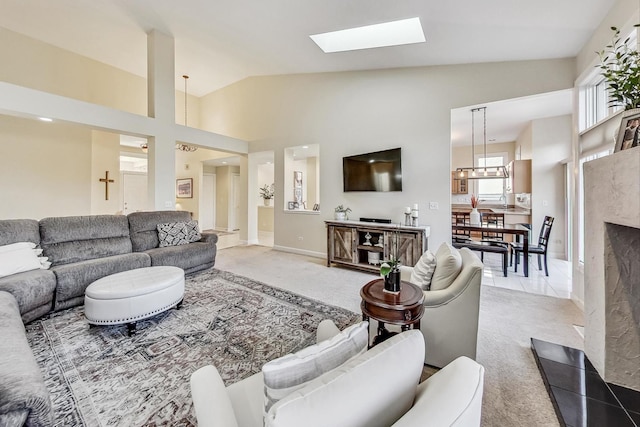 carpeted living room with high vaulted ceiling and a skylight