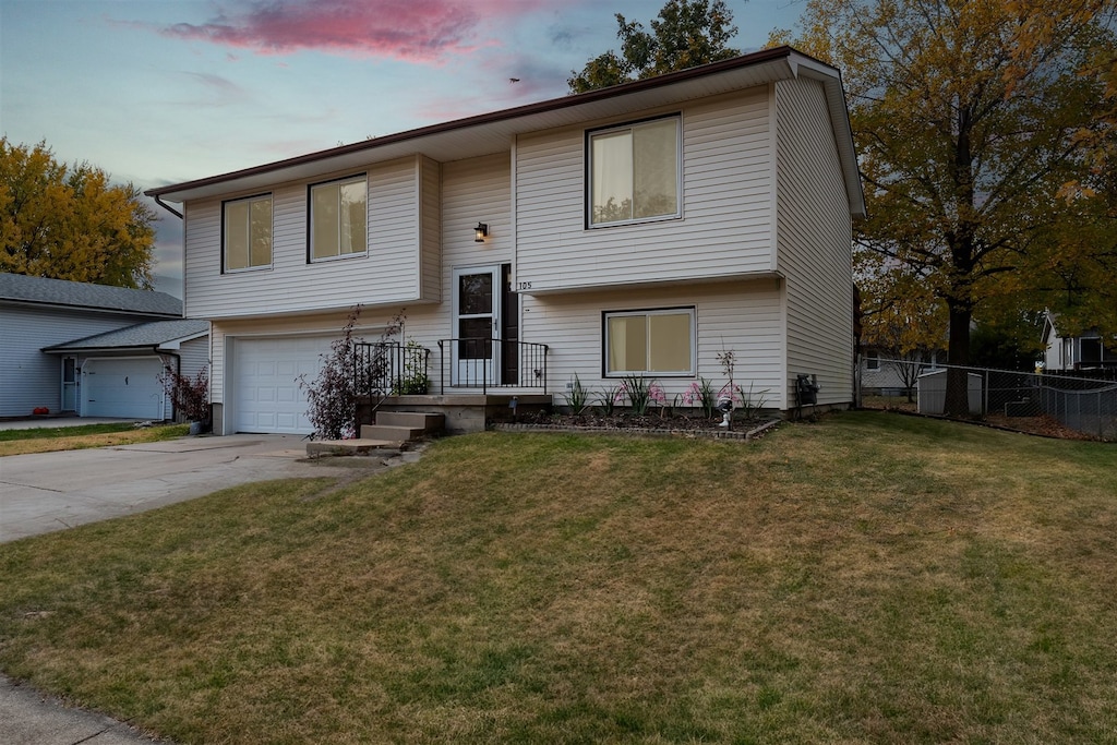 split foyer home featuring a garage and a lawn