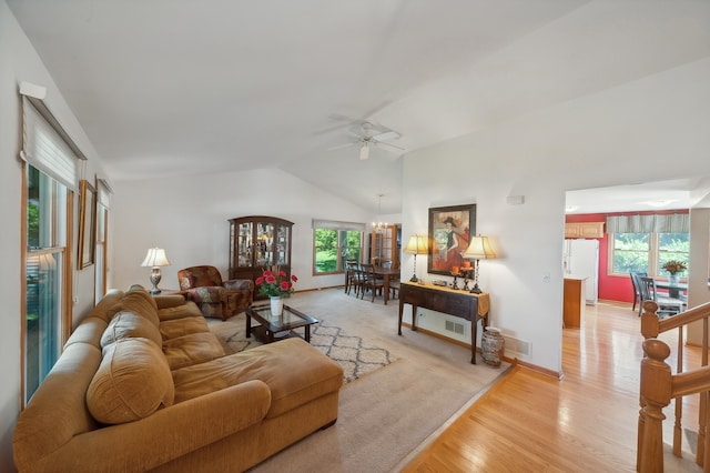 living room featuring light hardwood / wood-style floors, ceiling fan with notable chandelier, and vaulted ceiling