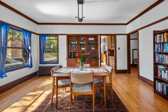 dining area with ornamental molding, baseboards, light wood-style flooring, and radiator heating unit