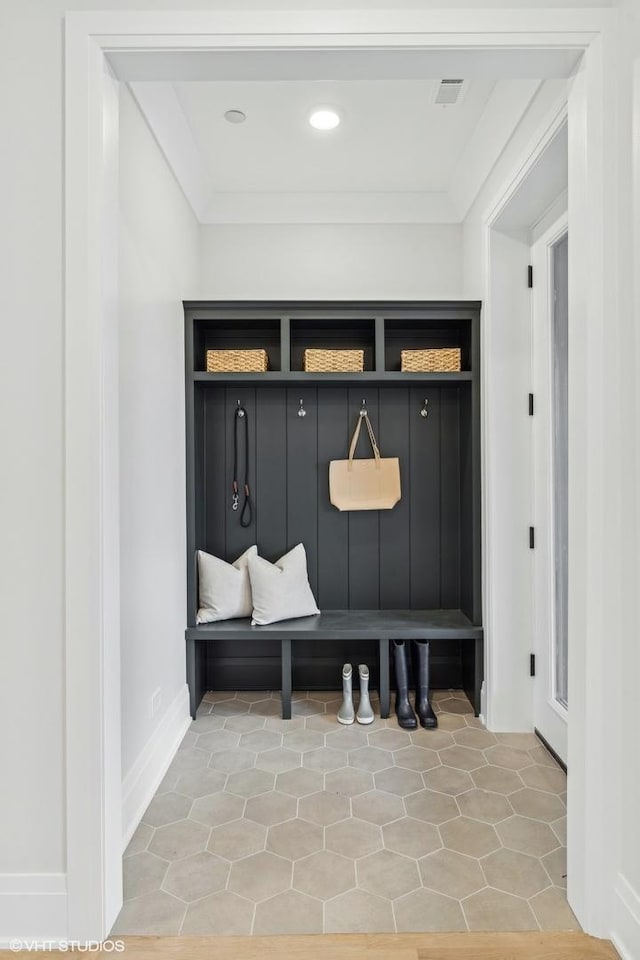 mudroom with tile patterned flooring and crown molding