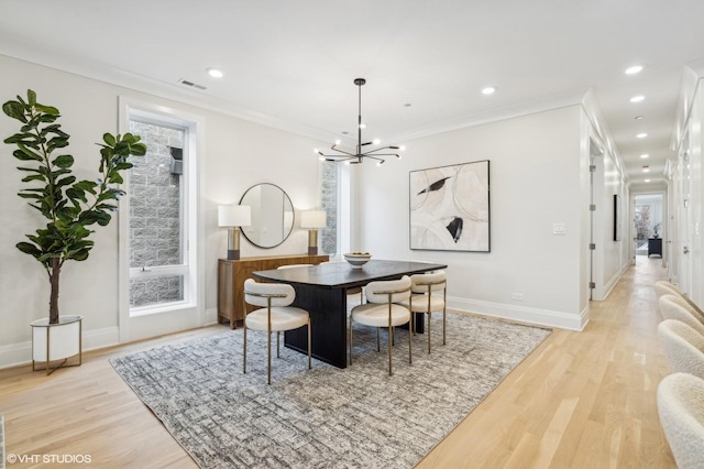 dining space featuring an inviting chandelier, crown molding, and light hardwood / wood-style flooring