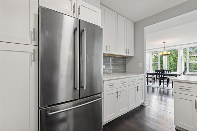 kitchen featuring stainless steel fridge, white cabinetry, dark hardwood / wood-style floors, and backsplash