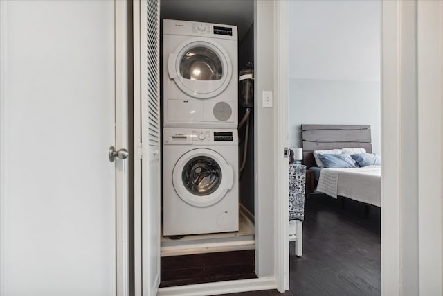 washroom featuring dark hardwood / wood-style flooring and stacked washing maching and dryer