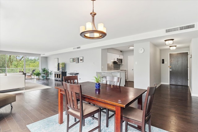 dining space with dark hardwood / wood-style flooring and an inviting chandelier