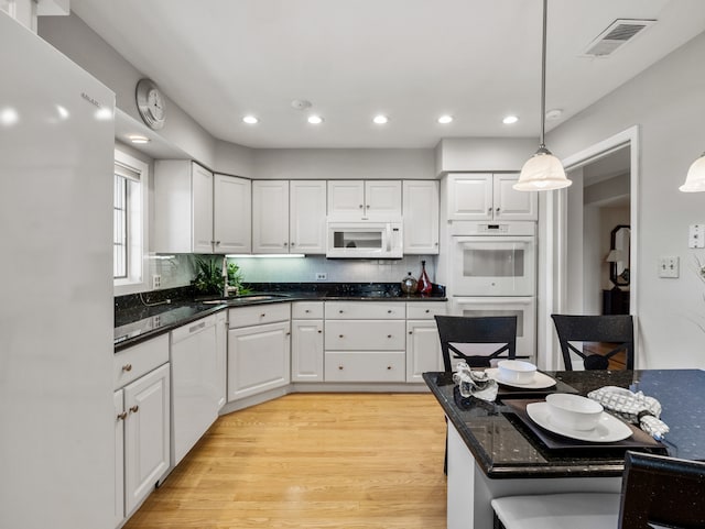 kitchen featuring hanging light fixtures, sink, light wood-type flooring, white cabinets, and white appliances