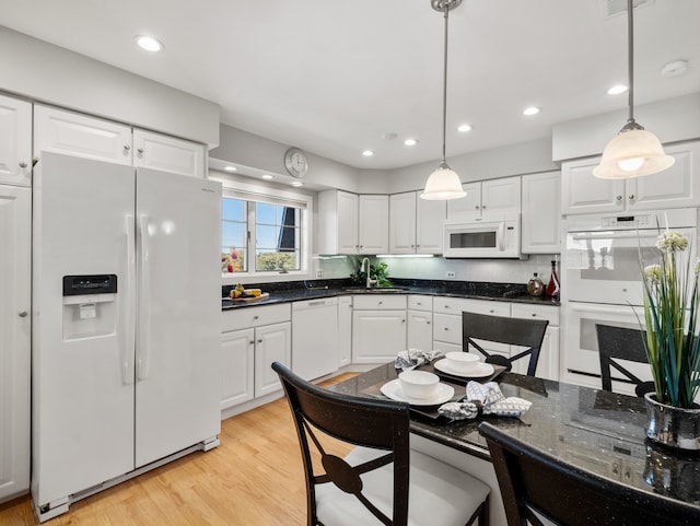 kitchen with white appliances, white cabinets, light hardwood / wood-style floors, and hanging light fixtures