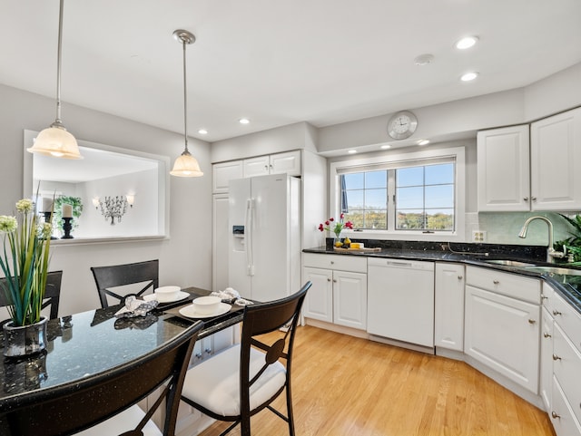 kitchen with white cabinetry, sink, decorative light fixtures, and white appliances