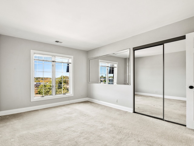 unfurnished bedroom with multiple windows, two closets, and light colored carpet