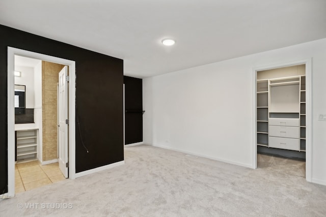 unfurnished bedroom with light colored carpet, connected bathroom, a closet, and a spacious closet