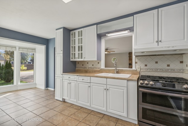 kitchen with decorative backsplash, white cabinetry, sink, and double oven range